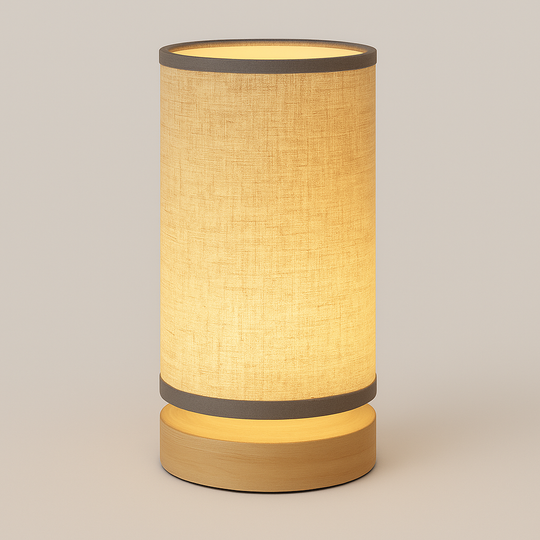 Cylindrical beige fabric table lamp with wood base and grey trim accents, glowing softly against a neutral studio background.