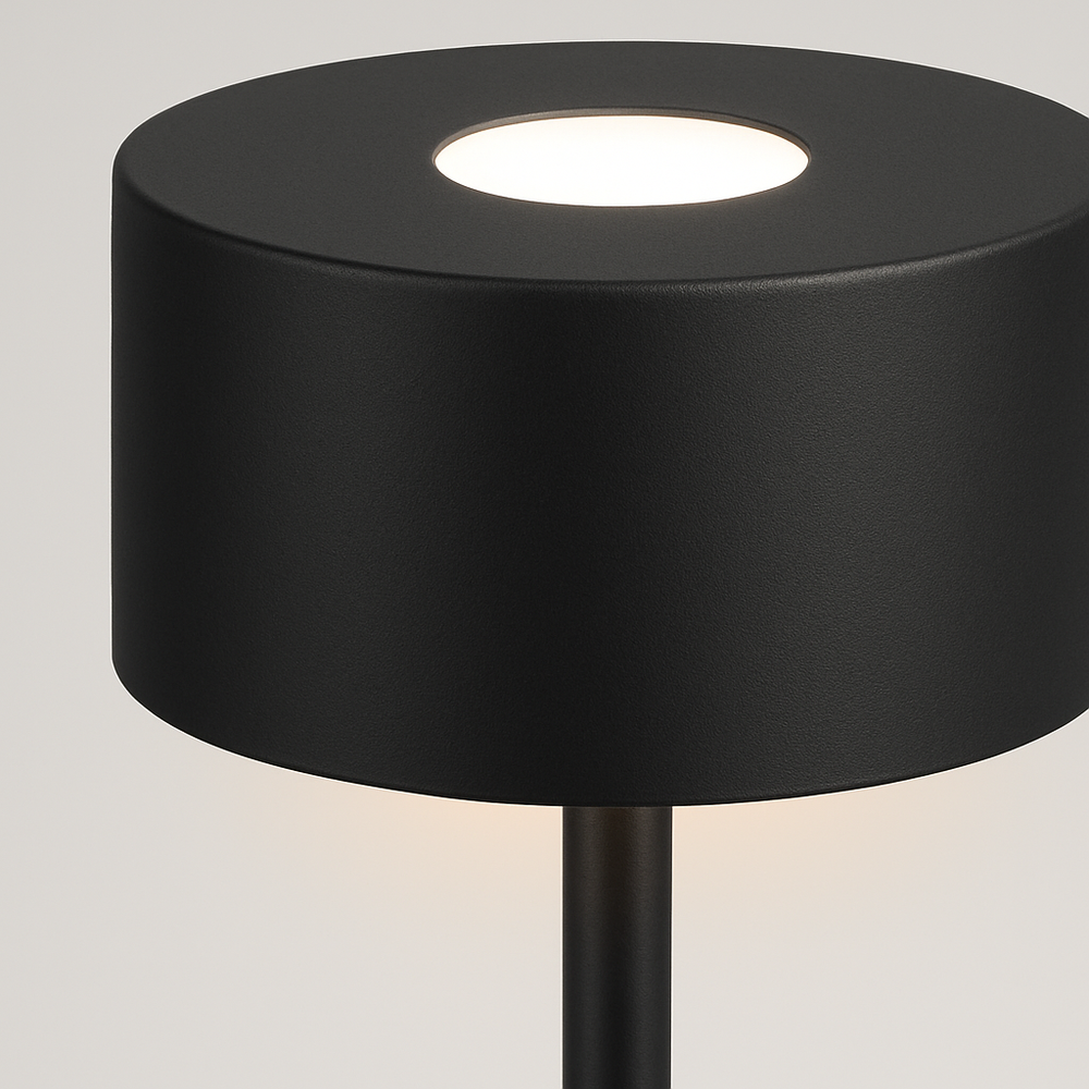 Modern black table lamp with cylindrical shade and slim stand, minimalistic design on a neutral studio background.