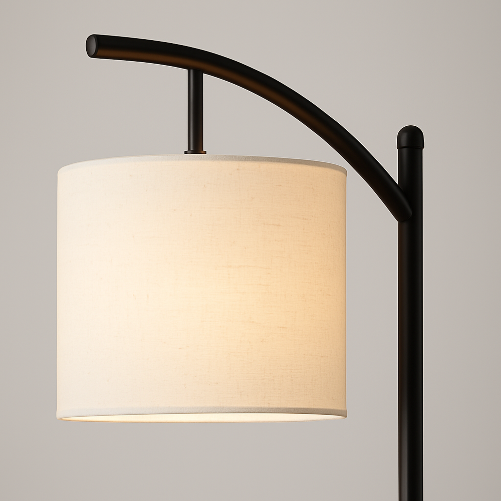 Tall arched floor lamp with black stand and ivory cylindrical shade, 158 cm in height, positioned beside an armchair in a cozy living room setting.