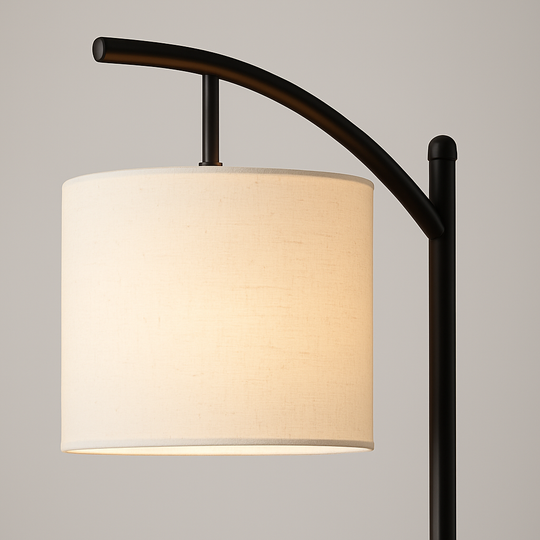Tall arched floor lamp with black stand and ivory cylindrical shade, 158 cm in height, positioned beside an armchair in a cozy living room setting.