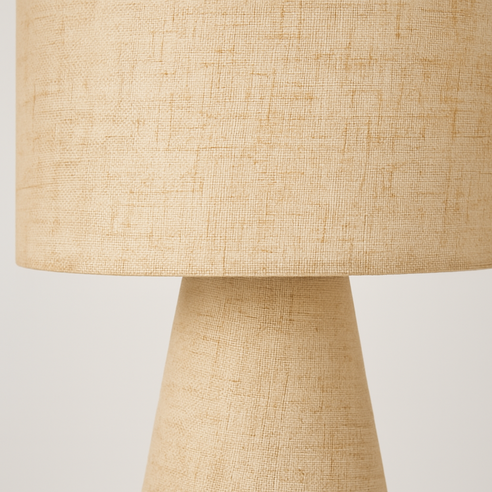 Beige linen table lamp with cylindrical shade and tapered base, shown against a clean studio background.